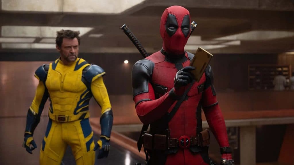 deadpool tient un appareil du tva et wolverine se tient derrière lui