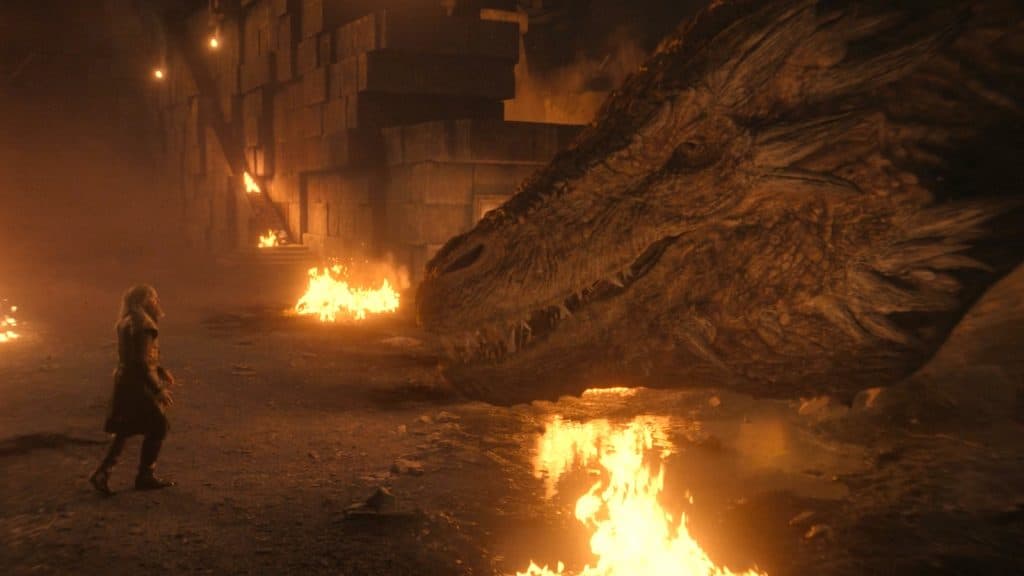 hugh marteau marche en direction de l'immense dragon vermithor, dans une grotte remplie de corps en feu